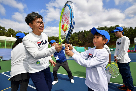 이대훈 NH농협은행 행장(왼쪽)이 캠프에 참여한 초등학생과 매직 테니스를 즐기고 있다.   NH농협은행 제공